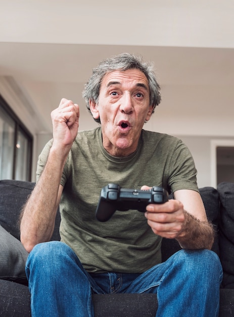 Free photo happy elderly man playing video game