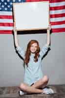 Free photo happy redhead young lady holding copyspace board