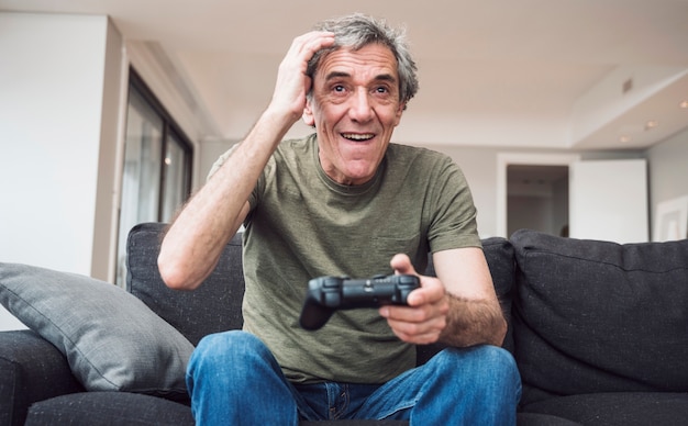 Free photo happy senior man playing video game at home