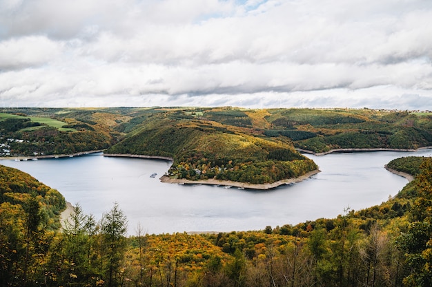 Бесплатное фото Высокий угол выстрела красивого озера, окруженного холмами осенью под облачным небом