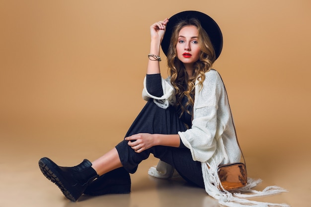 Free photo high fashion portrait of young elegant blonde  woman in black wool hat  wearing oversize white fringe  poncho with long grey dress.