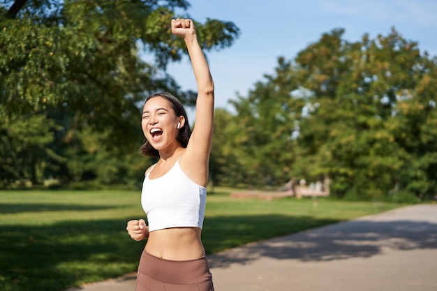 Free photo hooray victory smiling asian girl triumphing celebrating achievement running till finish shouting