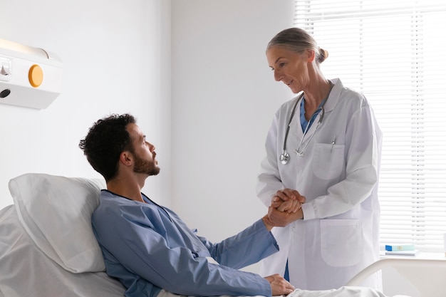 Бесплатное фото Больной пациент мужского пола в постели разговаривает с медсестрой