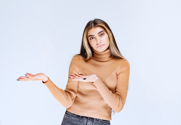 Бесплатное фото Изображение модели молодой женщины в коричневом свитере стоя и позирует.
