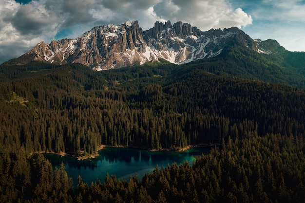 Бесплатное фото Карерзее в окружении лесов и доломитовых альп под облачным небом в италии