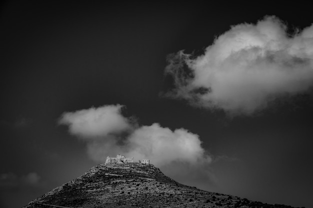 Long range shot of a mountain with houses on top in black and white