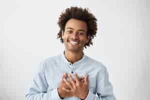Free photo lovely good-natured afro american man in white shirt having charming smile and friendly expression