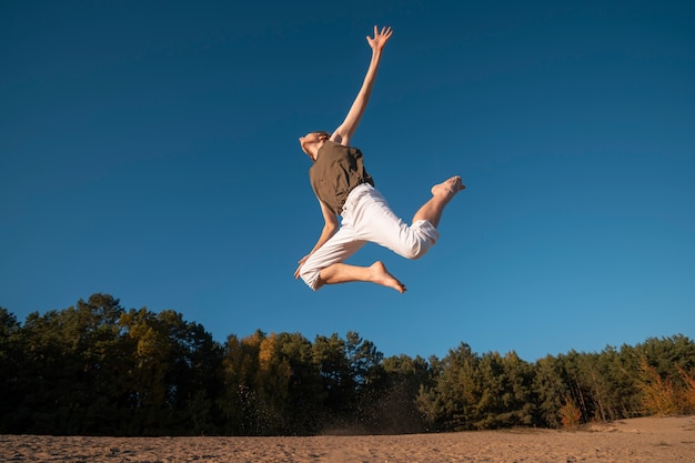 Бесплатное фото Человек прыгает на природе под низким углом