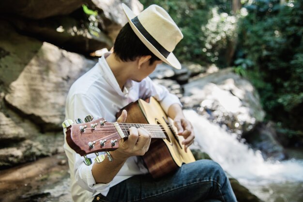 Человек играет на гитаре рядом с водопадом