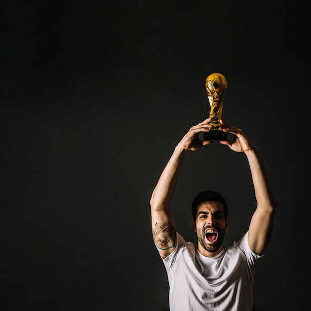 Бесплатное фото Человек с трофеем фифа празднует победу