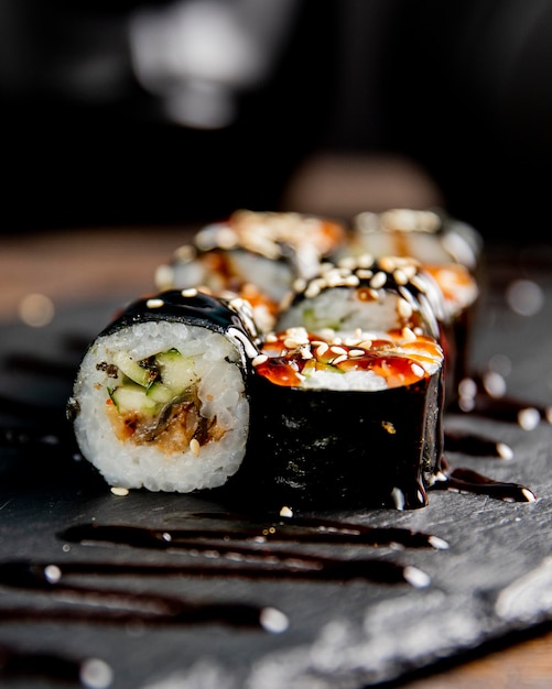 Free photo maki roll with cucumber served with sauce and sesame seeds