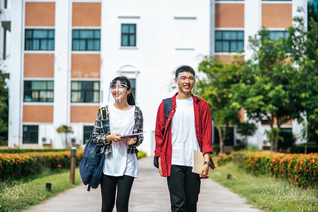 Бесплатное фото Студенты мужского и женского пола носят лицо chill и стоят перед университетом.