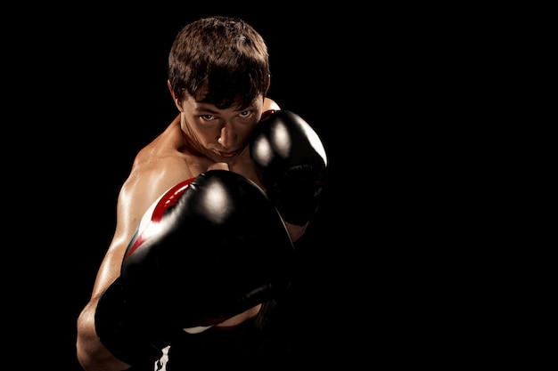 Бесплатное фото Мужской боксер бокс в боксерской грушей с драматическим острым освещением
