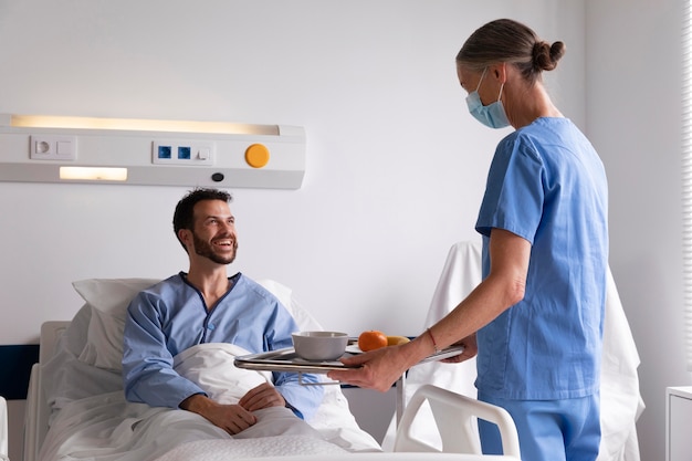 Бесплатное фото Пациент мужского пола в постели разговаривает с медсестрой