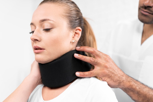 Бесплатное фото Мужской физиотерапевт надевает шейную скобу на женщину