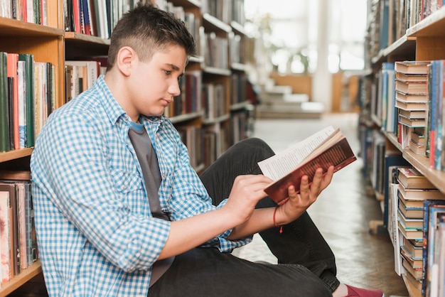 Мужчина подросток читает книгу на полу