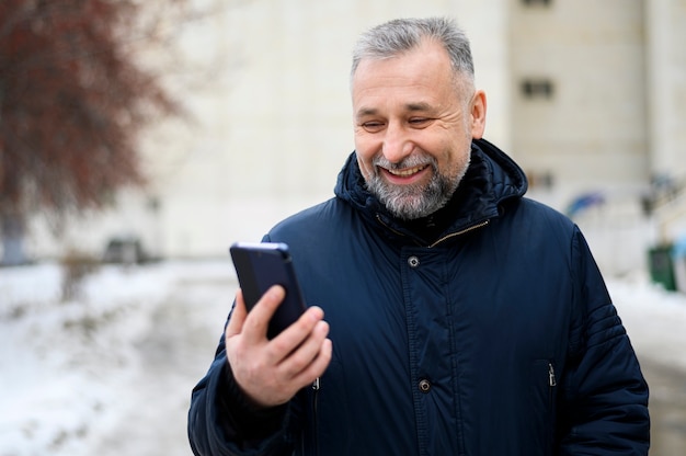 Бесплатное фото Зрелый человек, глядя на свой телефон на открытом воздухе