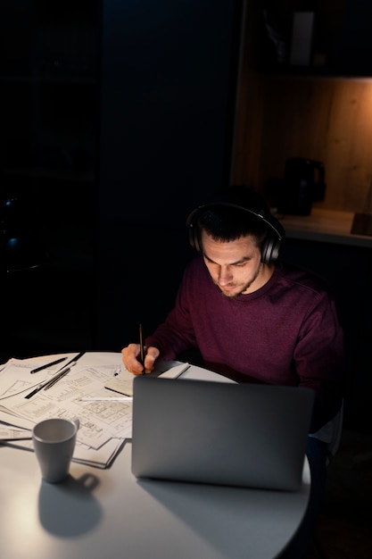 Мужчина среднего роста, работающий поздно ночью на ноутбуке