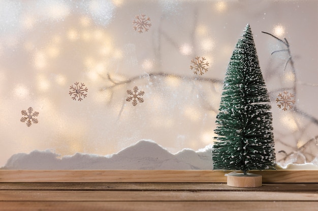 Бесплатное фото Украшение елки на деревянном столе возле банка снега, ветки растения, снежинки и сказочные огни