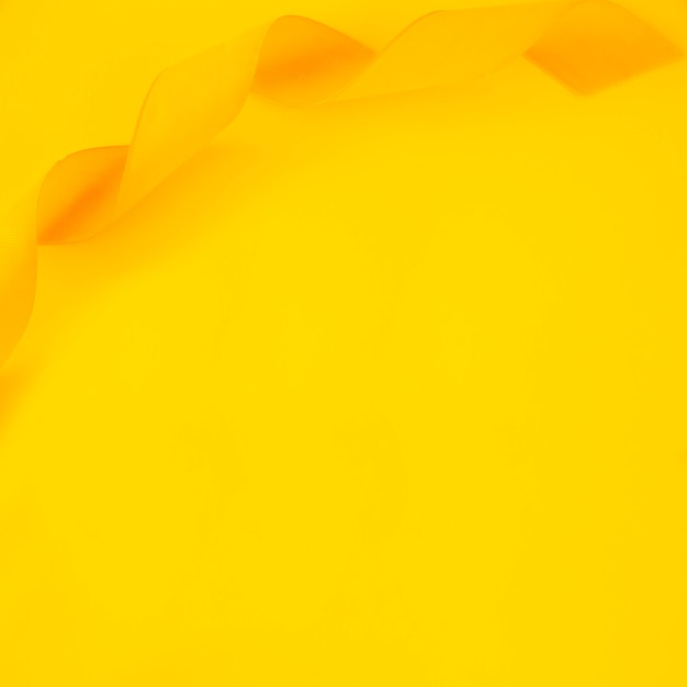 Верхний вид скрученной атласной ленты на желтом фоне