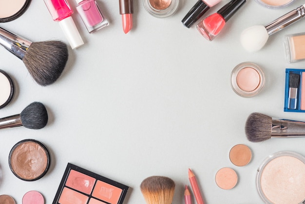 Overhead view of various makeup products forming circular shape on white background