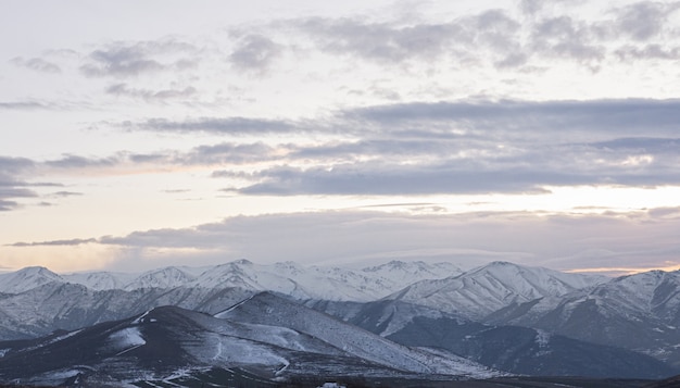 Бесплатное фото С видом на горы, покрытые снегом, с красивыми пейзажами заката в облачном небе.