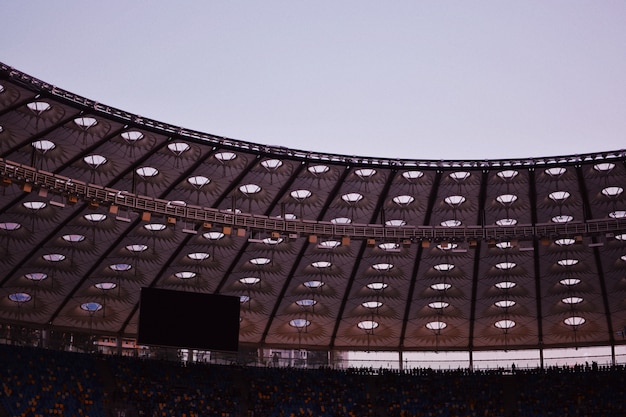 Бесплатное фото Частичный снимок стадиона с крышей, рядами сидений на большом мониторе и стульями