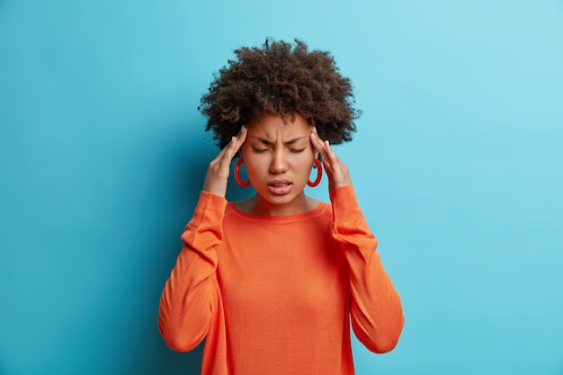 Free photo photo of frustrated young afro american woman has headache keeps hands on temples suffers unbearable migraine