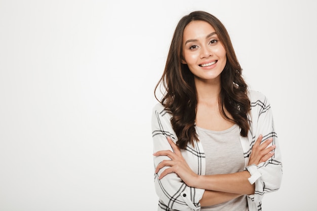 Free photo portrait of young woman with magnificent smile standing with arms folded isolated, over white
