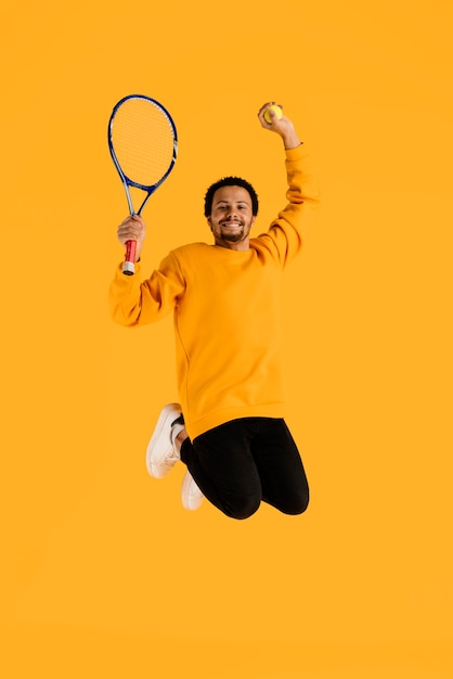 Бесплатное фото Портрет молодого человека прыгает с теннисной ракеткой
