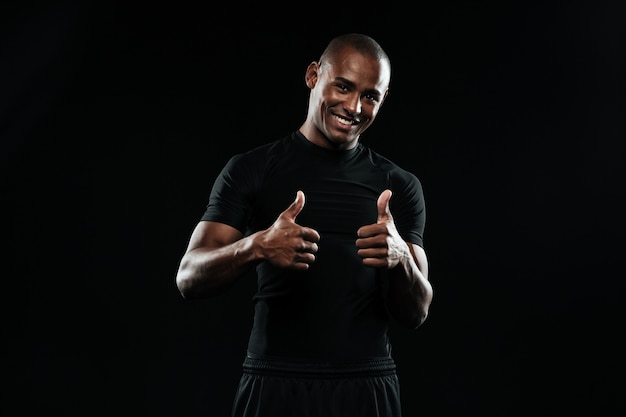 Портрет молодого улыбающегося африканского спортивного человека, показывает палец вверх