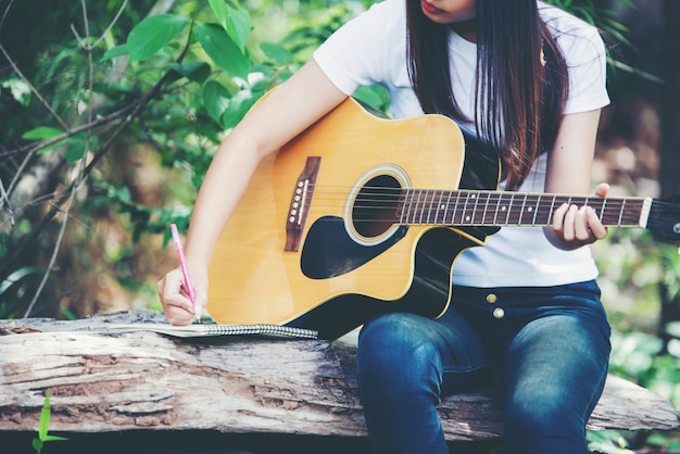 Портрет красивой девушки, играть на гитаре с написанием на природе