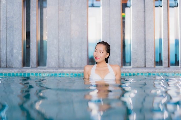 무료 사진 세로 아름 다운 젊은 아시아 여자는 traval 휴가에 호텔 리조트에서 수영장 주위에 미소를 긴장