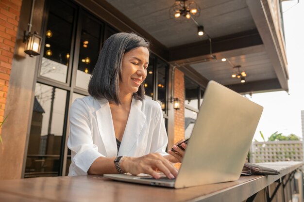 Portrait of businesswoman in a cafe using a laptop and a mobile phone