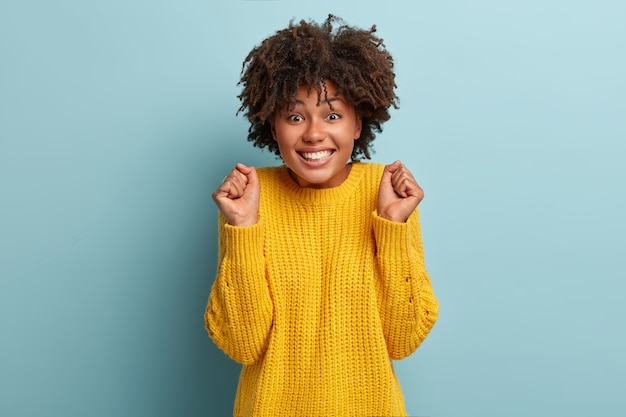 Free photo portrait of cheering woman with an afro posing in a pink sweater