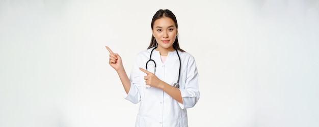 Foto gratuita ritratto dell'infermiera femminile in uniforme medica che punta le dita a sinistra mostrando il contenuto relativo all'ospedale h