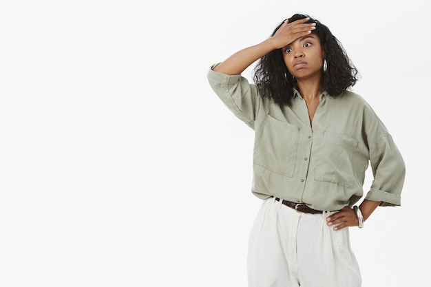Free photo portrait of fed up tensed and exhausted cute dark-skinned businesswoman in blouse and pants holding hand on waist exhaling