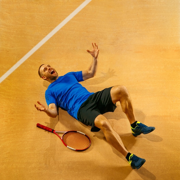 Free photo portrait of a handsome male tennis player celebrating his success on a court wall