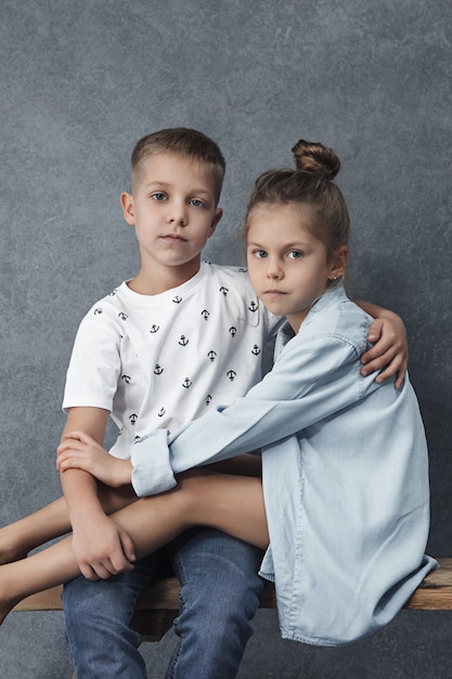 A portrait of little girl and a boy on the gray wall