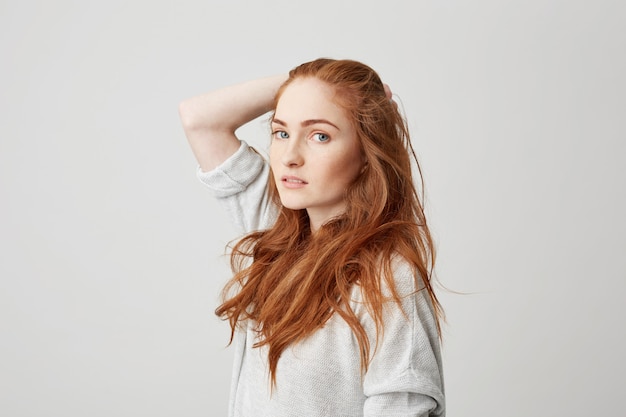 Бесплатное фото Портрет молодой довольно рыжая девушка с веснушками, касаясь волос.