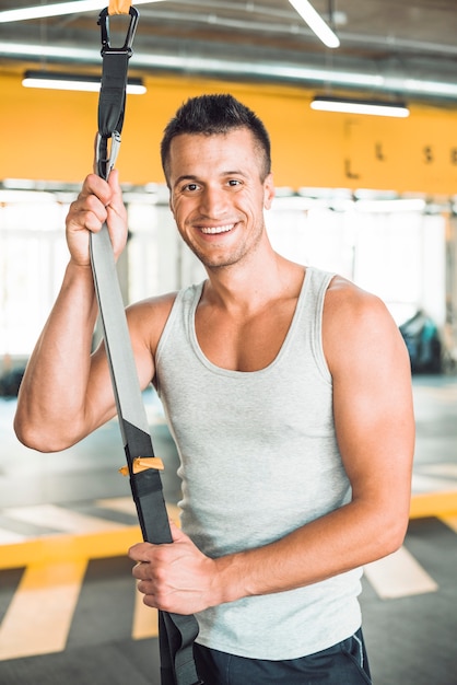 Бесплатное фото Портрет счастливого человека с фитнес-ремень в тренажерном зале