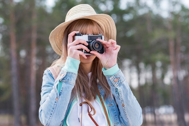 Бесплатное фото Портрет женщины в шляпе, принимая фото с ретро камеры