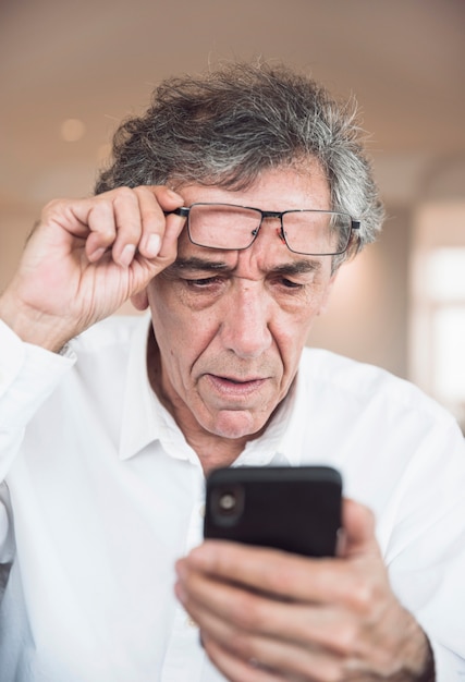 Free photo portrait of senior man looking at smartphone