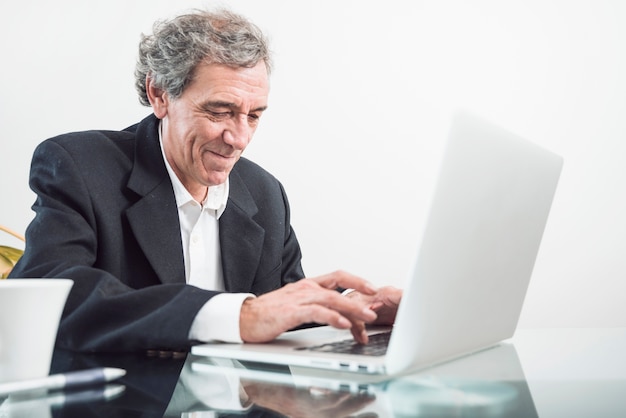 Free photo portrait of senior man typing on laptop in the office