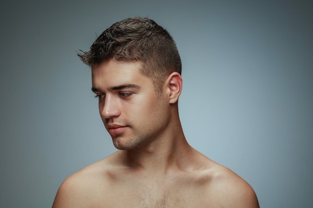 Free photo portrait of shirtless young man isolated on grey  background. caucasian healthy male model looking at side and posing.