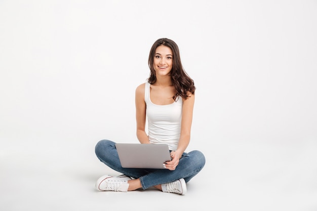 Free photo portrait of a smiling girl dressed in tank-top holding laptop