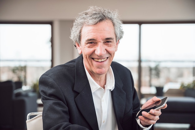 Free photo portrait of smiling senior man holding smart phone