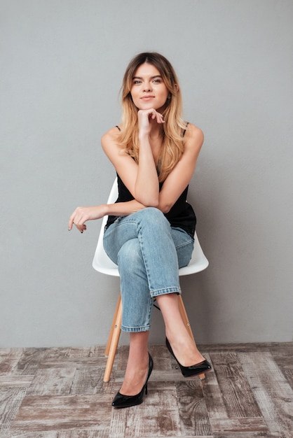 Free photo portrait of a smiling woman sitting on a chair