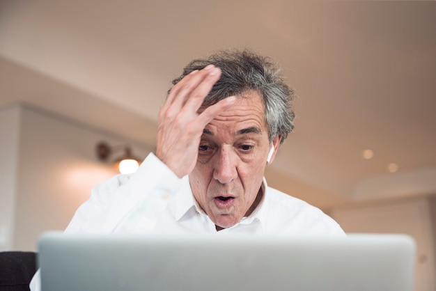 Portrait of surprised senior man looking at laptop
