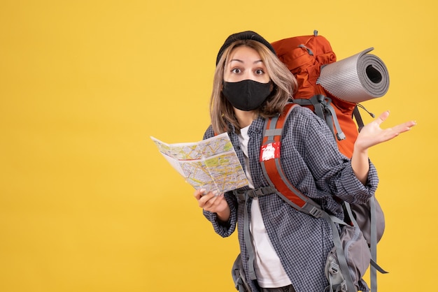 Бесплатное фото Озадаченная девушка-путешественница с черной маской и рюкзаком держит карту